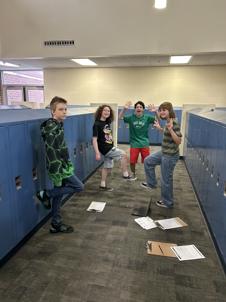 A group of four students are working together. Three of the four are  balancing on one foot (because the fourth student is timing them, though his computer is not shown). 