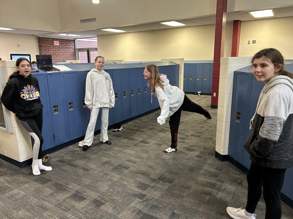 One girl holds a yoga pose while the others observe / time her. 