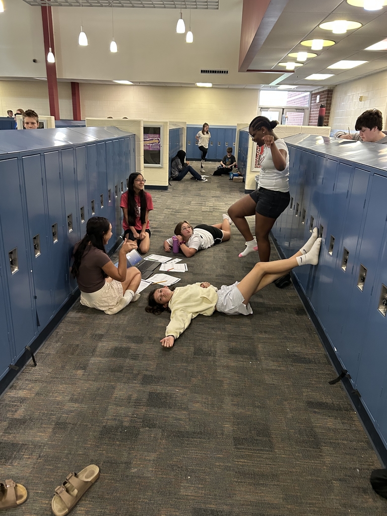 One girl holds a yoga pose while the others observe / time her. 
