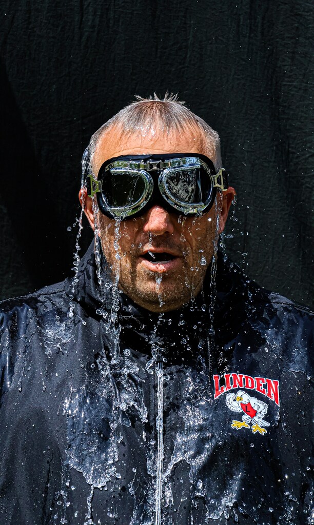 water balloon popped over guys head in black with water cascading down over him