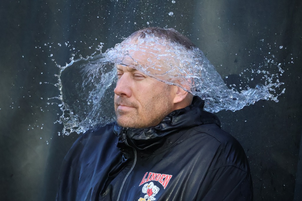 water balloon popped over guys head in black with water cascading down over him