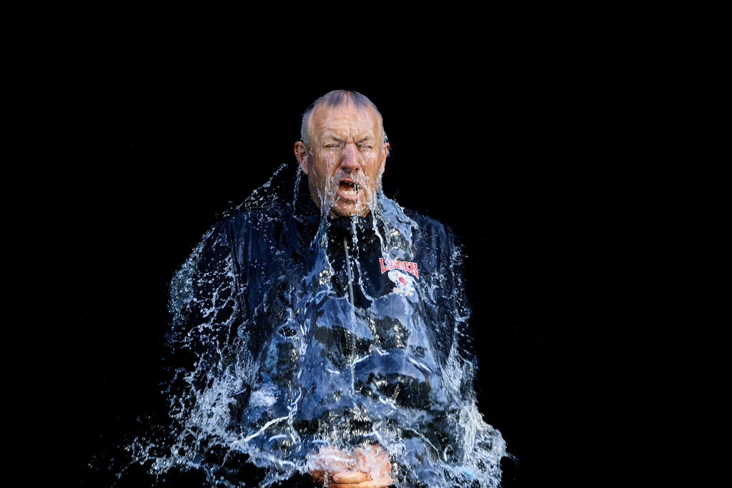 water balloon popped over guys head in black with water cascading down over him