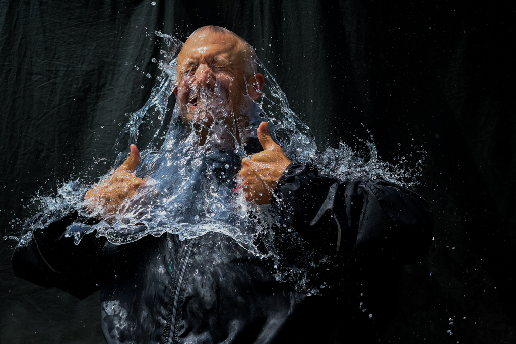 water balloon popped over guys head in black with water cascading down over him