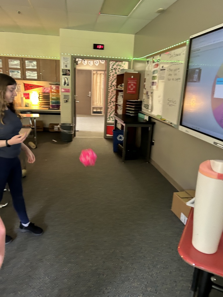 A student rolling a soft, multi sided die in a classroom.