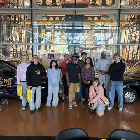 students standing in front of automobiles