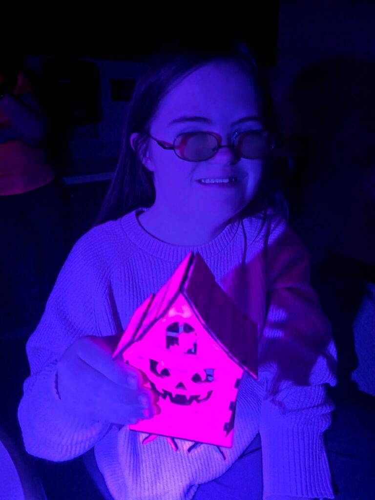 Student holding up her glowing, spooky house.