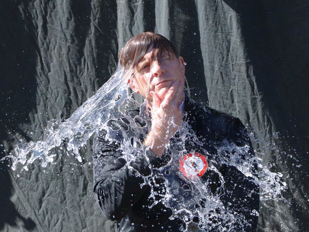 Person with hand on chin and water cascading all over them.