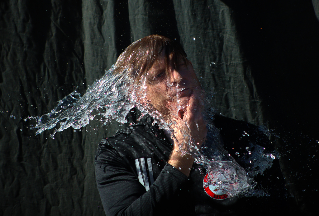 Person with hand on chin and water cascading all over them.