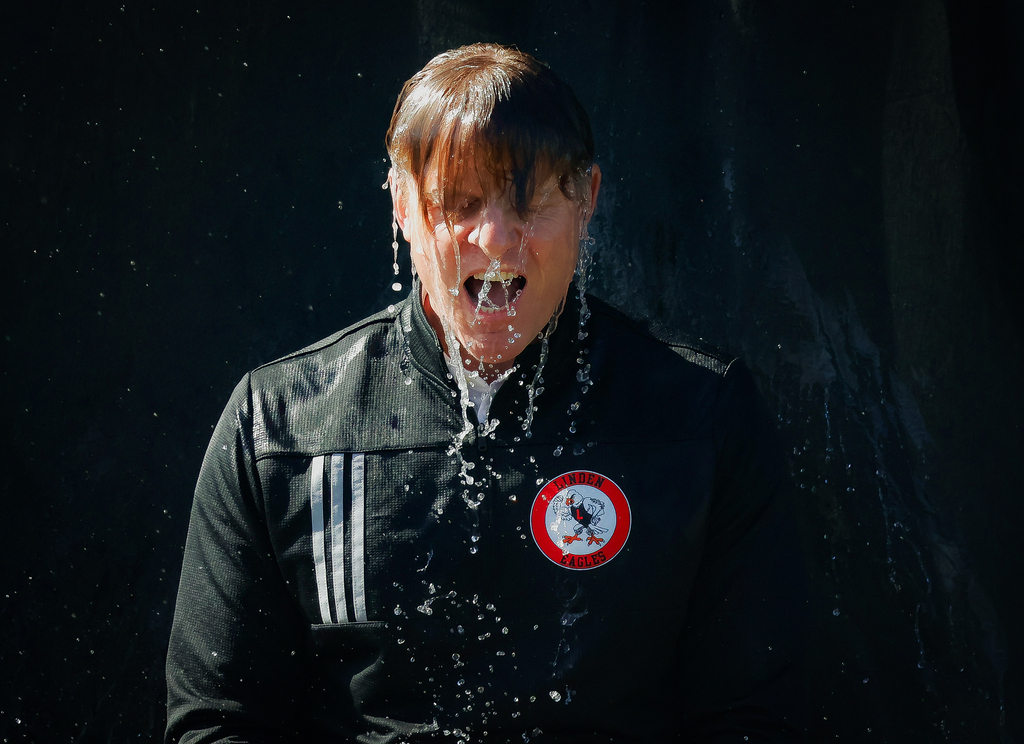 Person with water dripping off head on black background