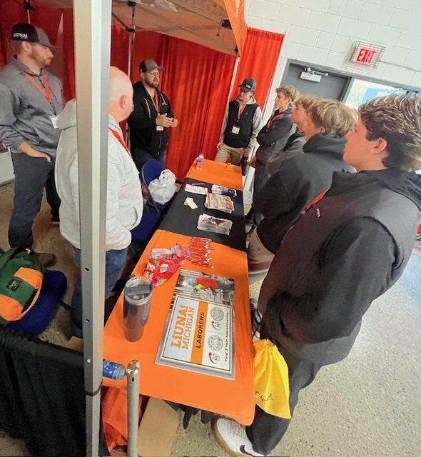 Students standing by a table talking with LiUNA tradesman learning about their career pathways.