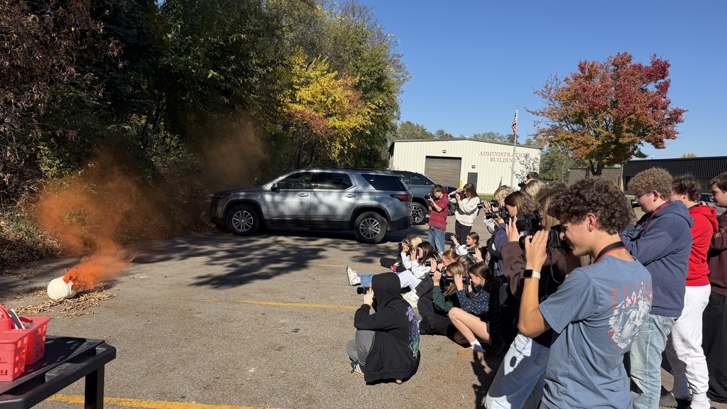 Students taking photos of pumpkins with smoke in a parking lot.