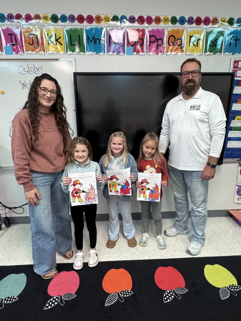 First-grade students pose for a class photo recognizing the Fire Prevention Week coloring contest winners. First-place winner Avery Bosch, second-place winner Kelsie Wald, and third-place winner Harper Holzer are recognized. The contest was sponsored by the local fire department.