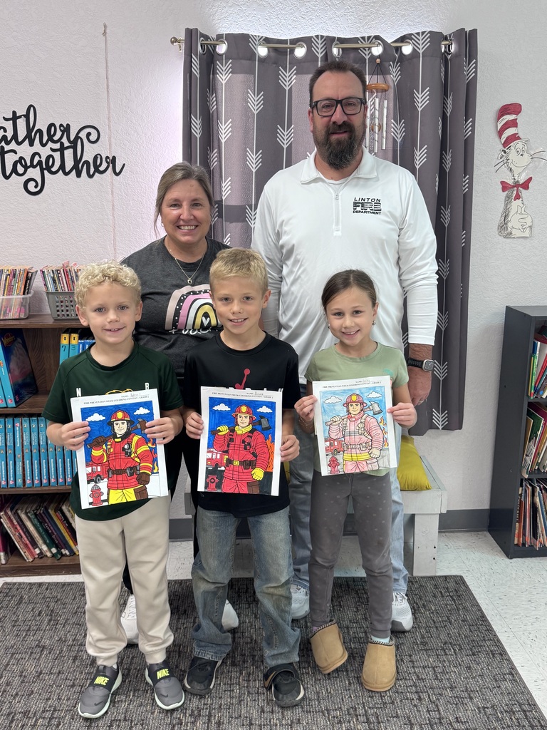 First-grade students pose for a class photo recognizing the Fire Prevention Week coloring contest winners. First-place winner Avery Bosch, second-place winner Kelsie Wald, and third-place winner Harper Holzer are recognized. The contest was sponsored by the local fire department.