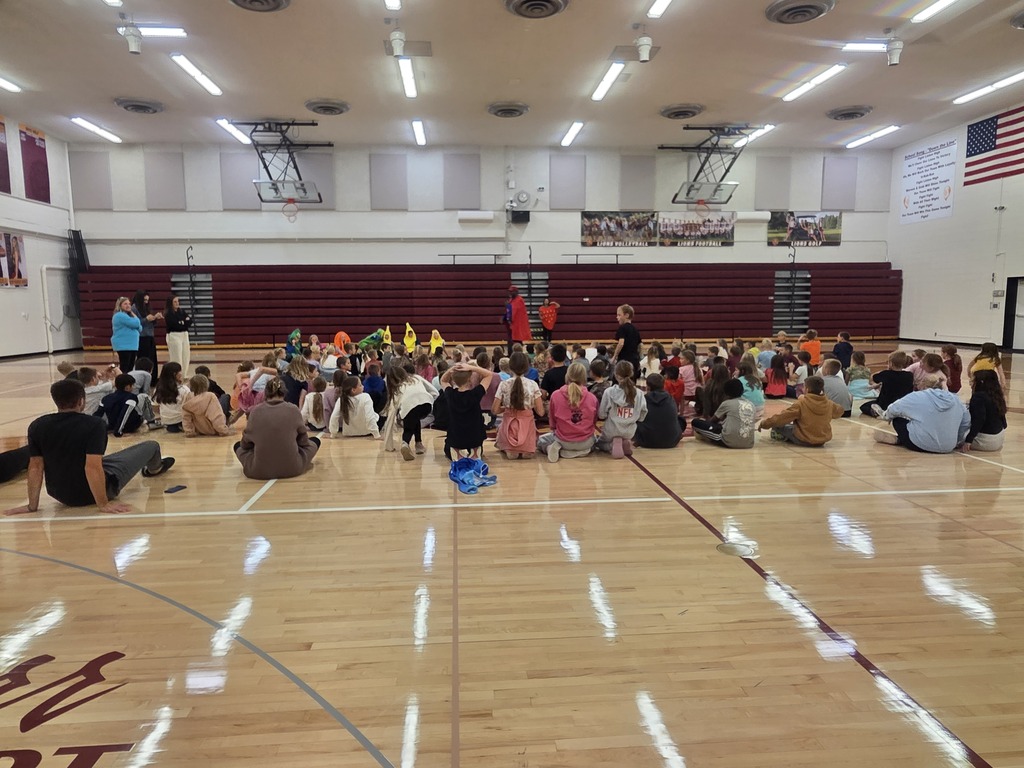 Elementary students gather in the school gym during an interactive visit from Super Apple Man, a superhero who teaches students about healthy food choices.