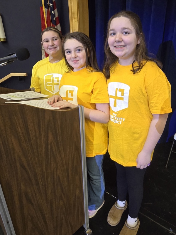 Three students standing at a podium
