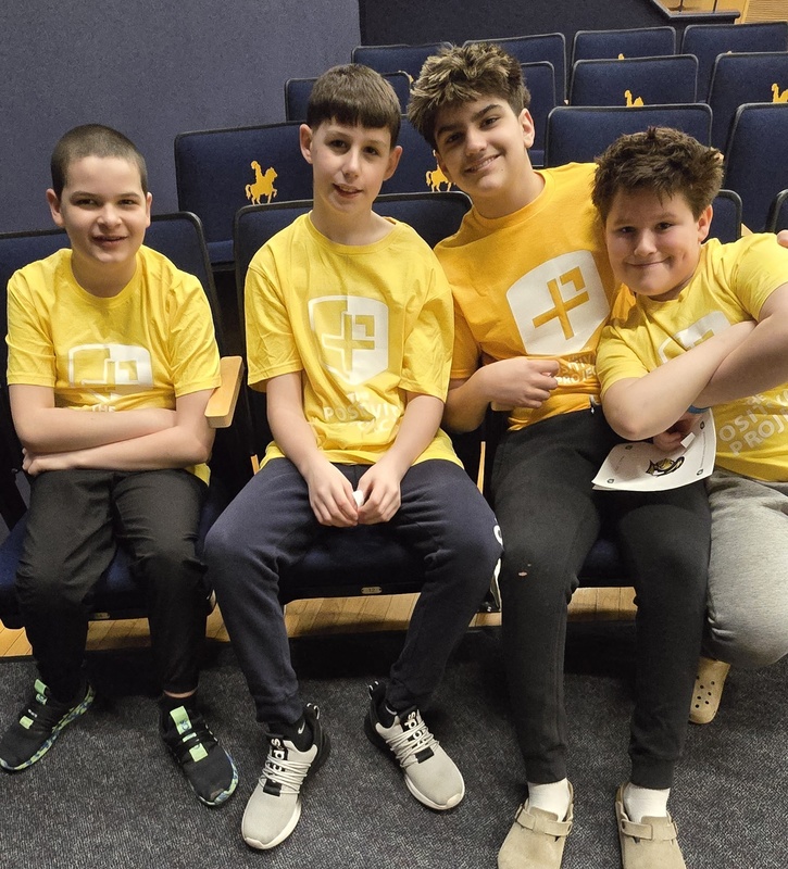 Students posing in their yellow shirts in auditorium seating