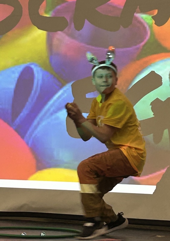 Student in bunny ears hopping like a rabbit in front of a festive easter background