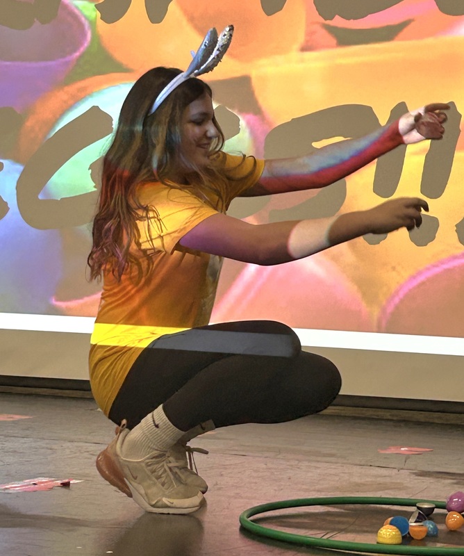 Student in bunny ears hopping like a rabbit in front of a festive easter background