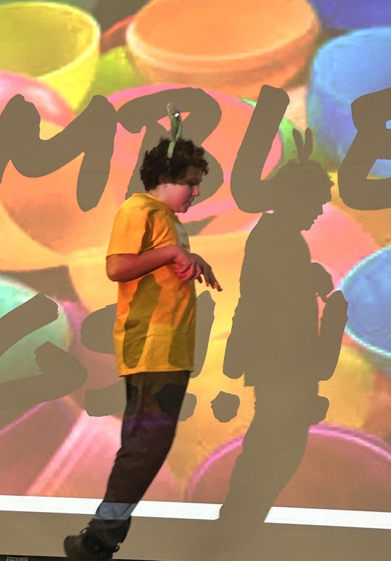 Student in bunny ears hopping like a rabbit in front of a festive easter background