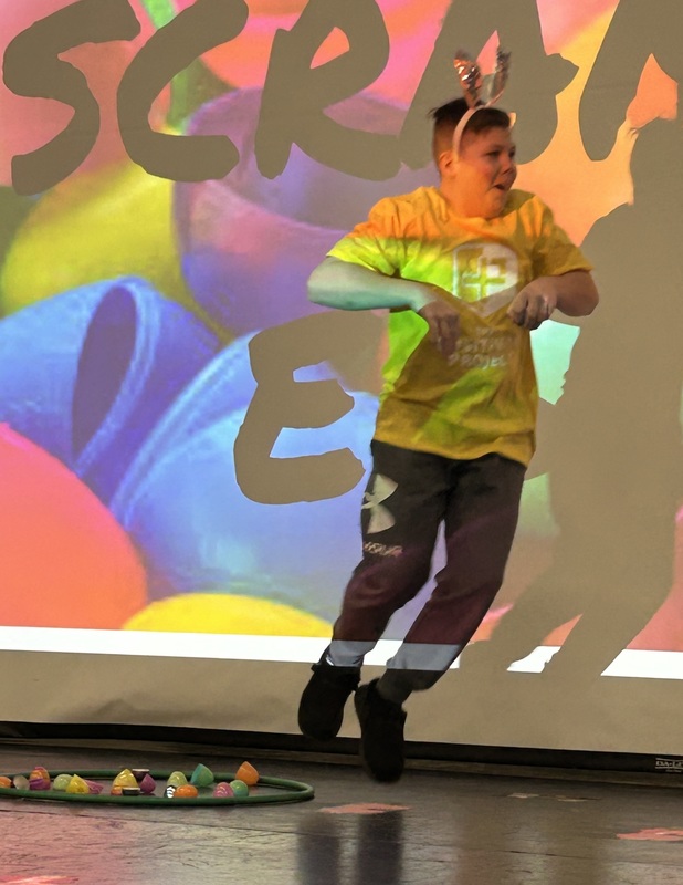Student in bunny ears hopping like a rabbit in front of a festive easter background