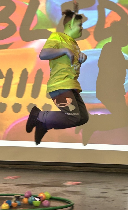 Student in bunny ears hopping like a rabbit in front of a festive easter background