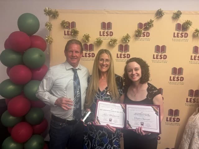 Image shows three teachers standing holding awards