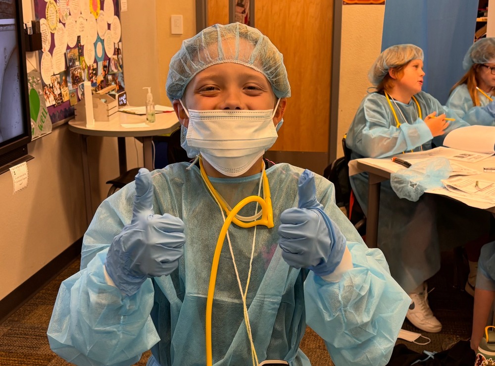 Image of male student wearing hospital gown, gloves and face mask.