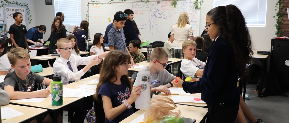 Students learn at desks from a high school student