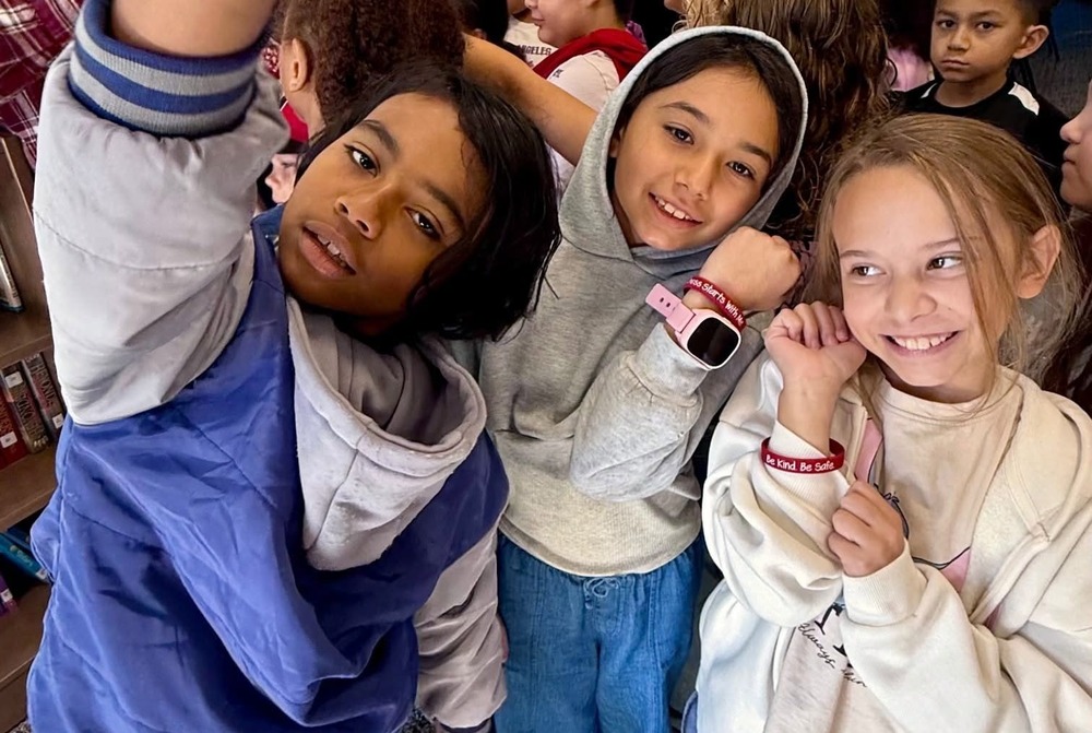 Children smiling and showing off kindness bracelets