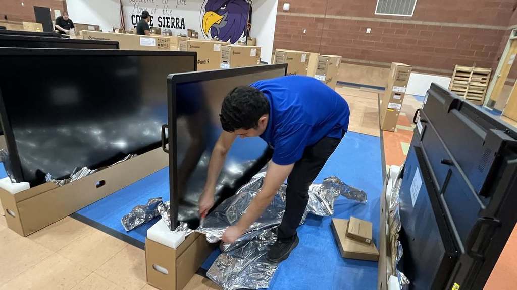 IT member unpacking monitor screen