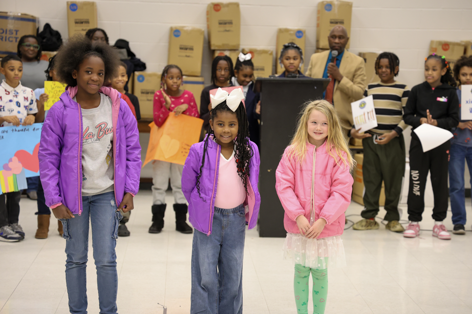 Three girls at Dr. Martin Luther King, Jr. Leadership and Language Academy show off the coats delivered to all students at the school. 