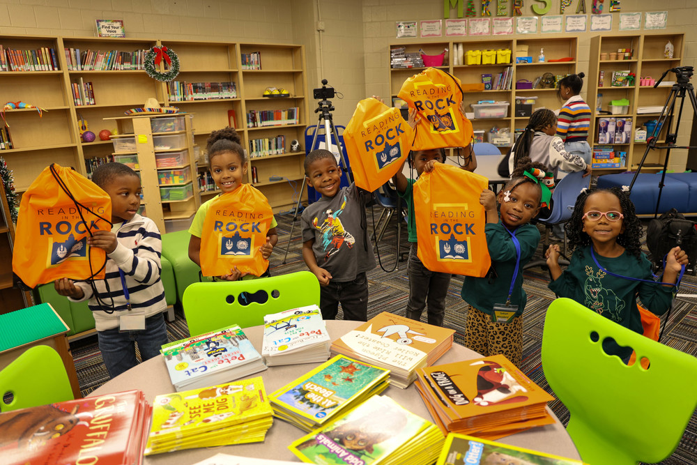 Students at JA Fair hold up their Reading in the Rock bags after a book distribution at JA Fair