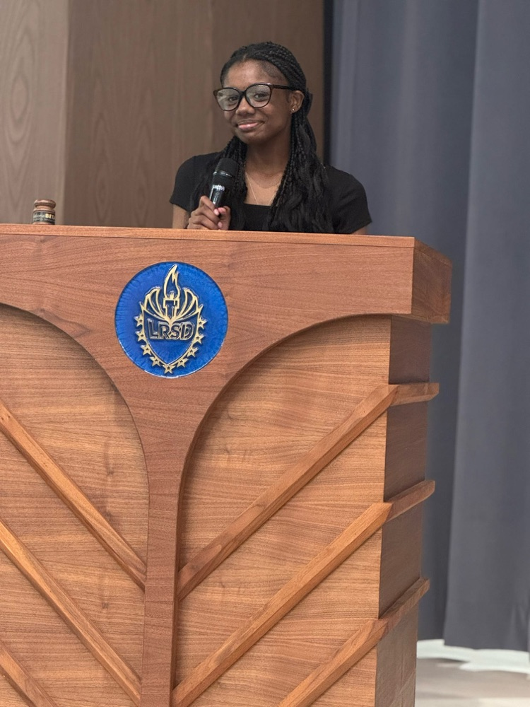The treasurer is standing at the podium, giving a speech