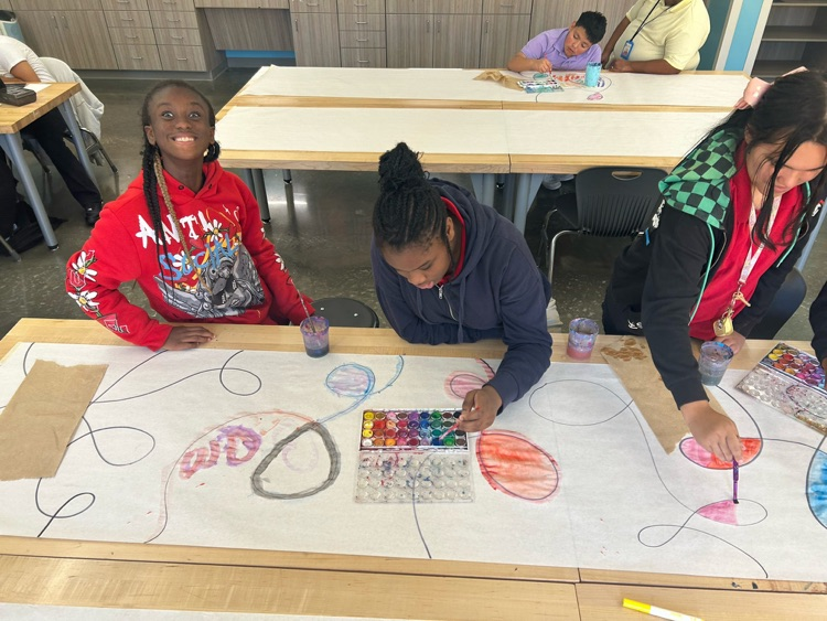 Students drawing on big paper in art class 