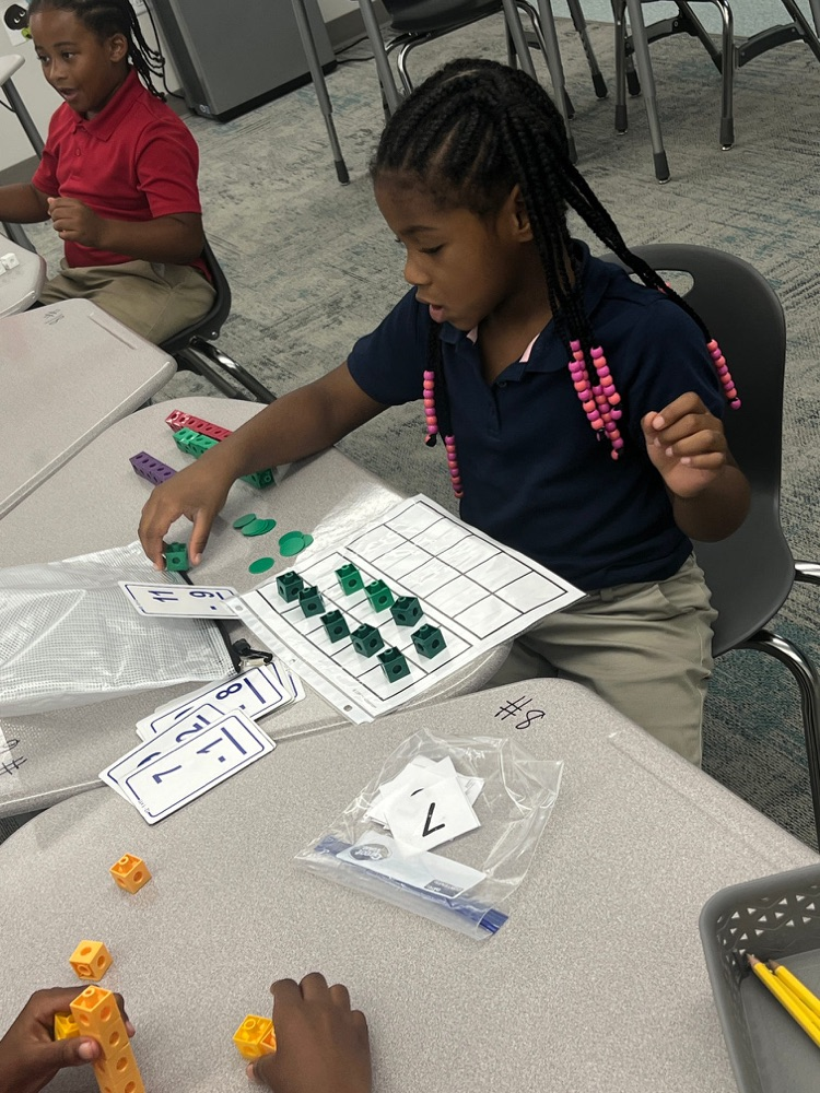 A 1st grade is using manipulatives to do math  