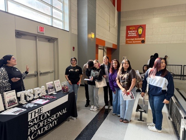 A group of students listen to a recruiter from The Salon Professional Academy 