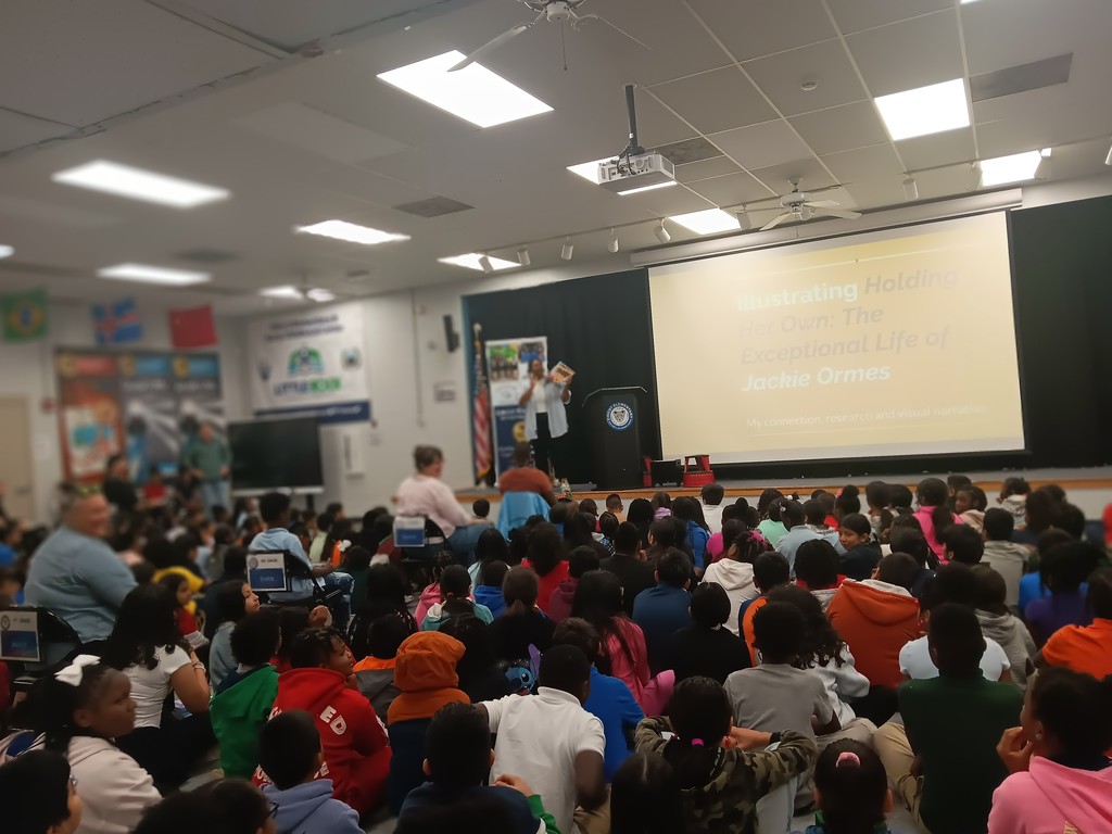 Image of author talking to an assembled group of students. 