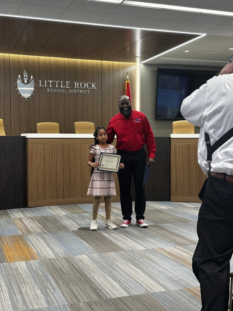 Student is holding a certificate next to the superintendent