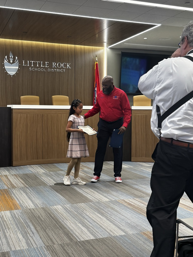 Student is holding a certificate next to the superintendent