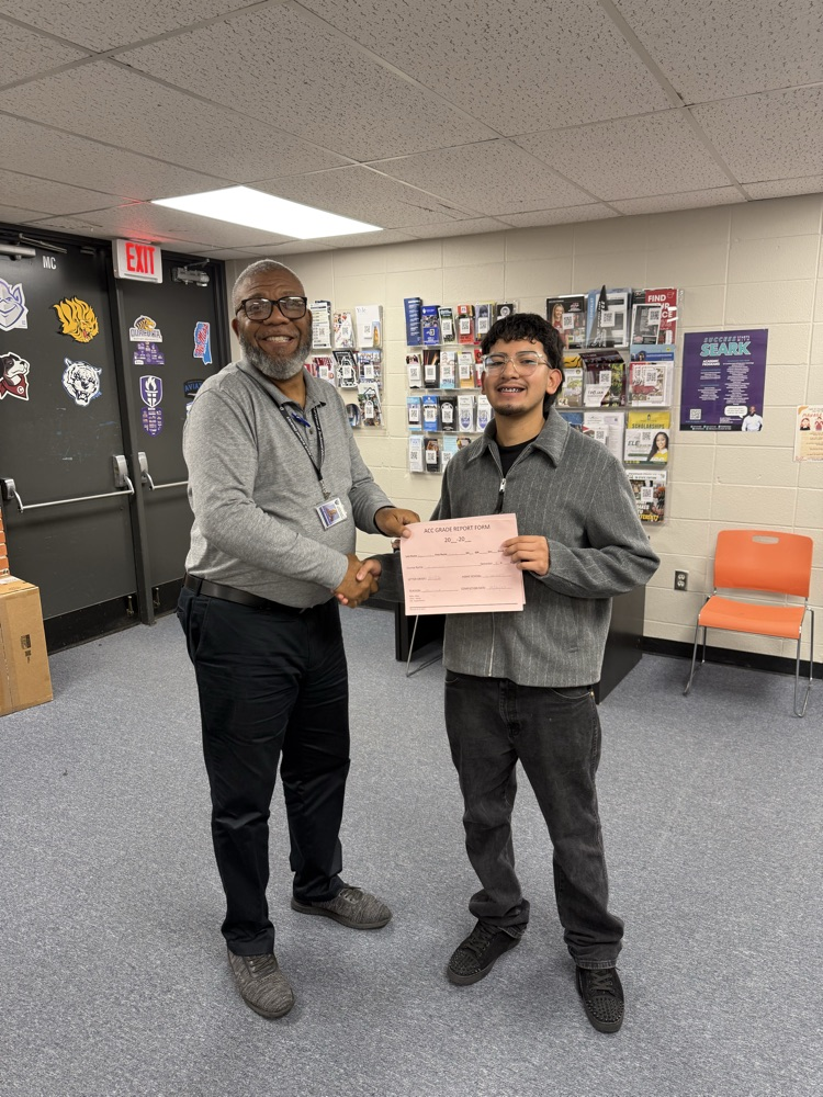 Kevin and Mr. Henderson shaking hands. with Kevin holding his completion forms  
