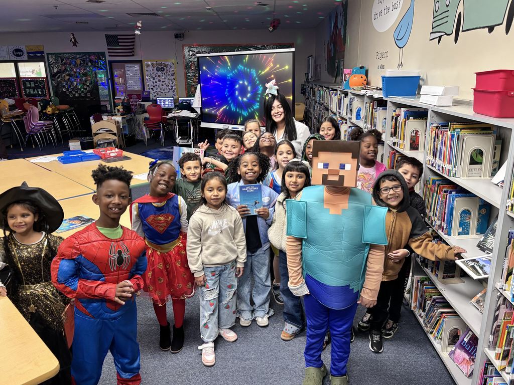 Image of a group of students smiling in book character costume with their teacher. 