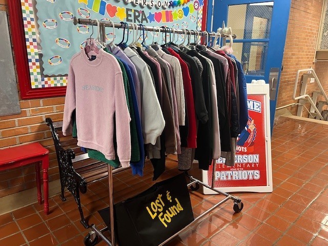 Picture of kids' jackets, coats, sweaters, hoodies, and pullovers hanging on a clothes rack. 