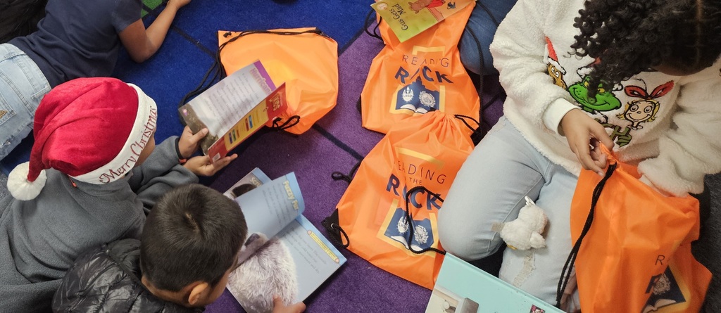 Image of students looking at new books received through the Readin in the Rock reading initiative 