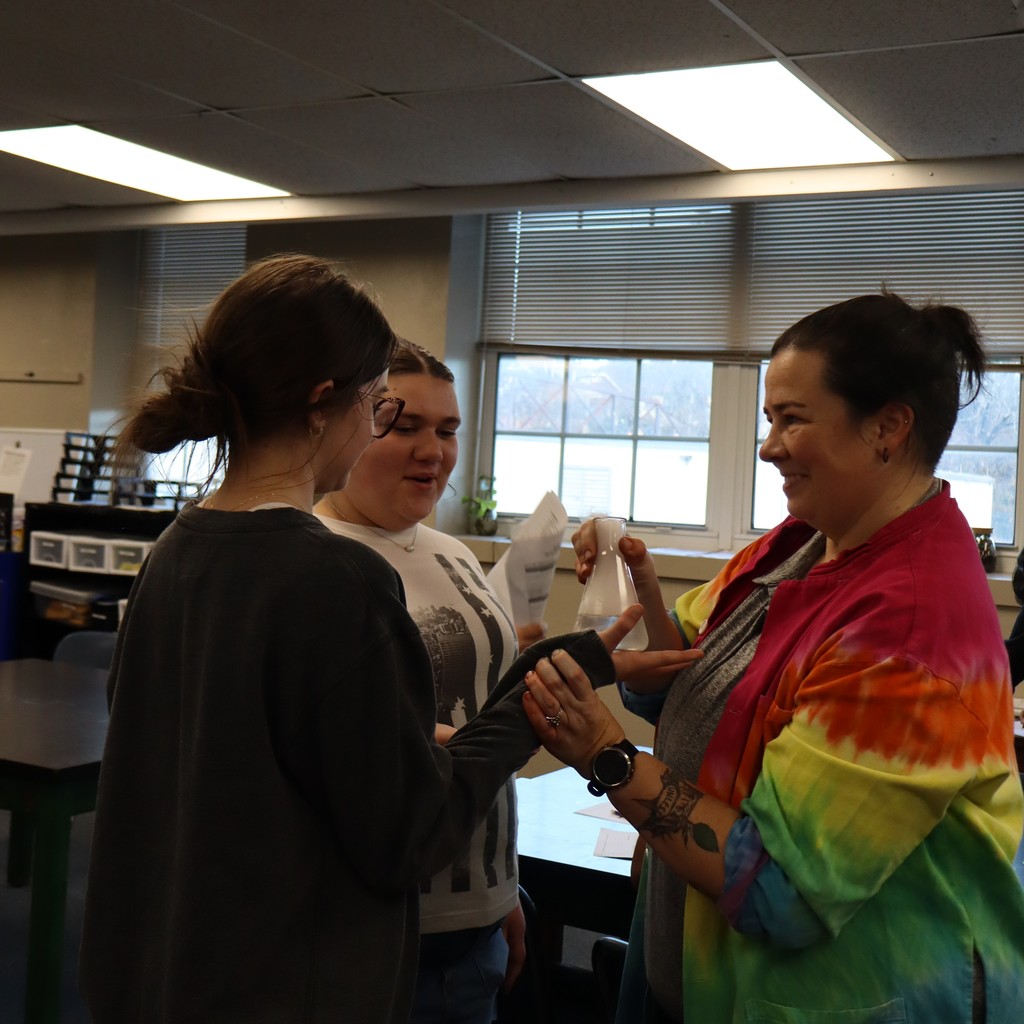 A student reaching out to feel the effect of the chemical reaction on the glass of a beaker