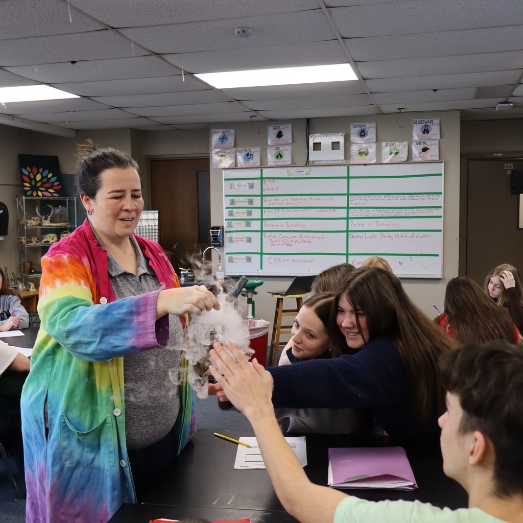Students reaching out to move their hands through the CO2 gas