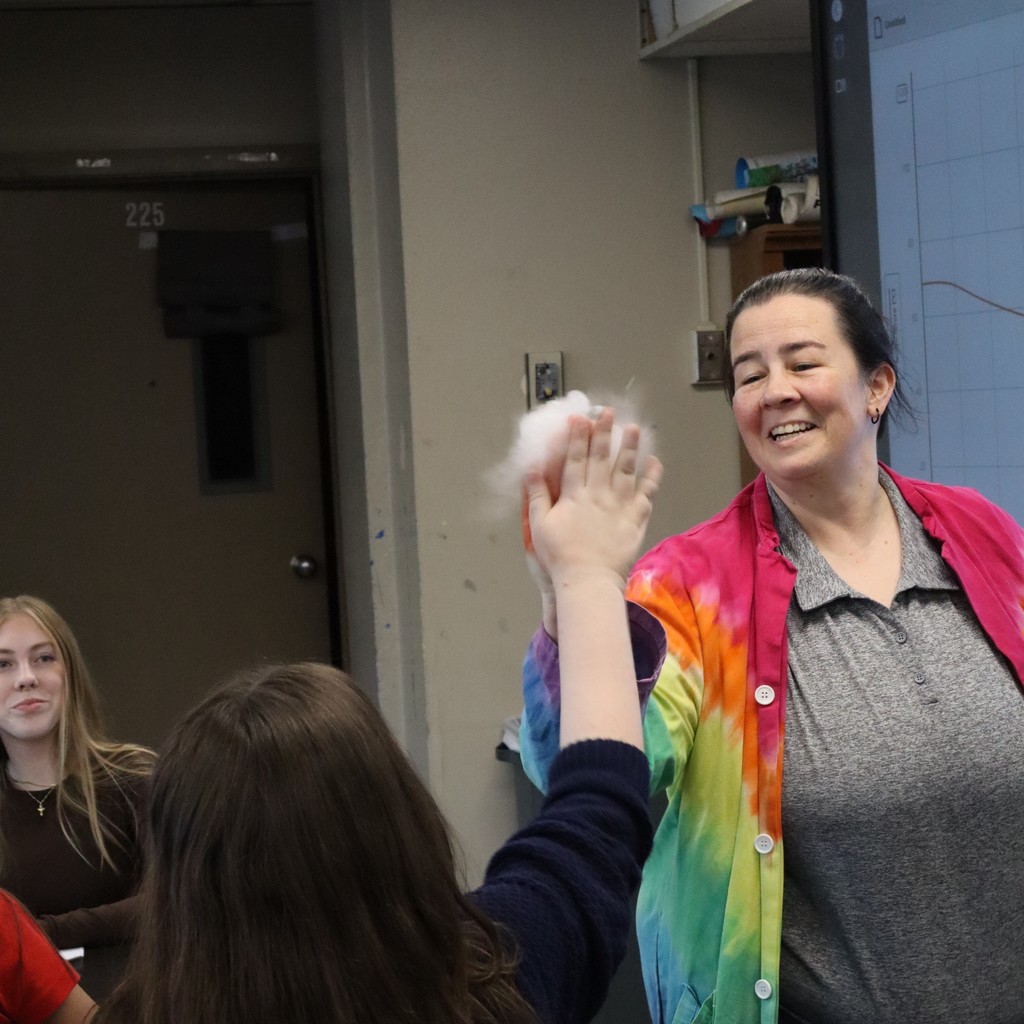 Mrs. Scott high-fiving a student with bubbles filled with carbon dioxide