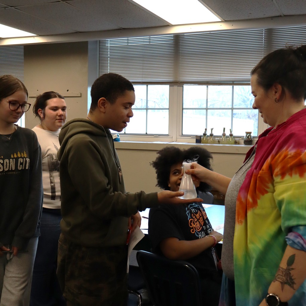 A student reaching out to feel the effect of the chemical reaction on the glass of a beaker