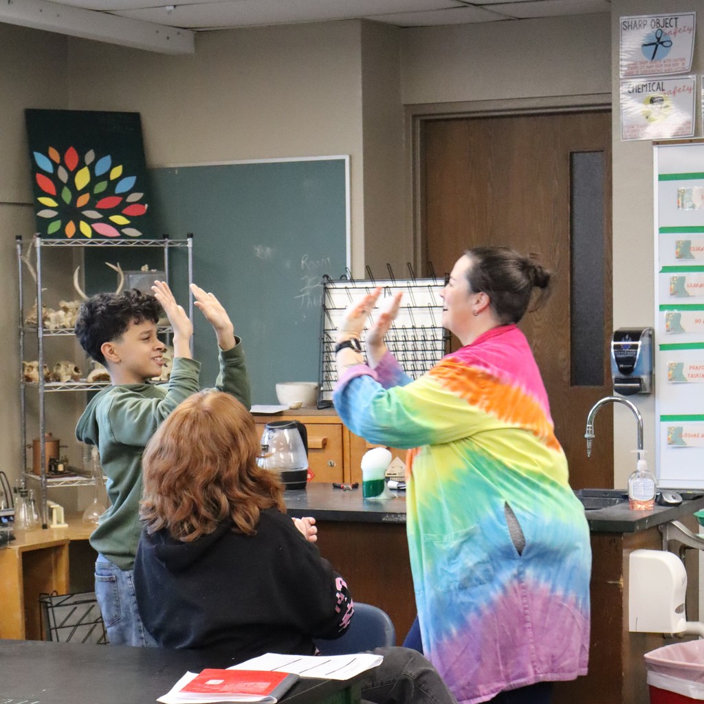 Mrs. Scott high-fiving a student with bubbles filled with carbon dioxide
