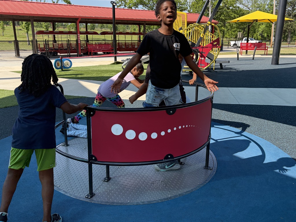a group of students playing on the merry go round at the park
