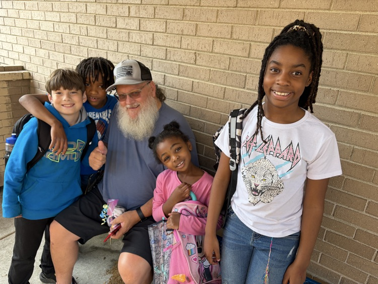 a few student surround their bus driver with a treat bag